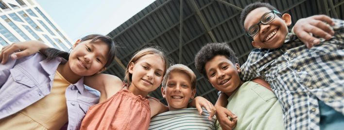 Joyful multicultural group of children smiling and embracing, showcasing friendship and diversity.