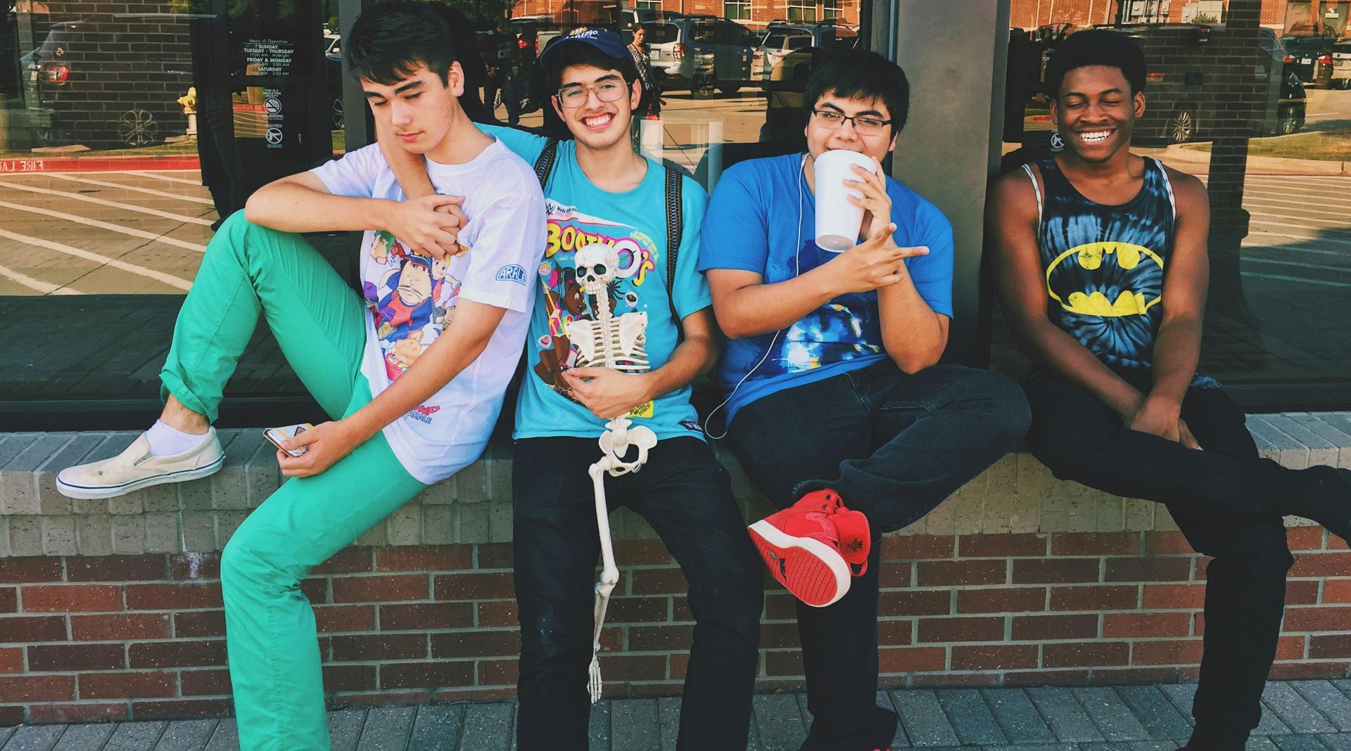 Group of teenage friends sitting outdoors, smiling and having fun together.